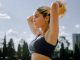 A focused woman in sportswear tying her hair, preparing for an outdoor workout in Mexico City.