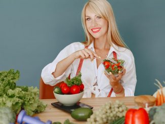 Blonde woman enjoying a fresh salad surrounded by vegetables, promoting healthy eating.
