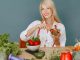 Blonde woman enjoying a fresh salad surrounded by vegetables, promoting healthy eating.